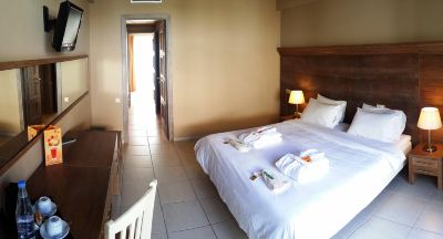 a well - lit bedroom with a white bed , white sheets , and towels neatly folded on the bed at Valley Village