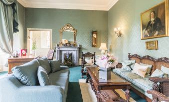 a spacious living room with a couch , coffee table , and a fireplace in the center at Coombe Abbey Hotel