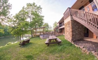 a serene outdoor setting with a wooden deck , picnic table , and deck chairs under the shade of trees at Skyline Lodge