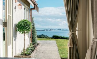 a beautiful view of a lake from a balcony , with trees and grass in the foreground at Mudbrick Cottages