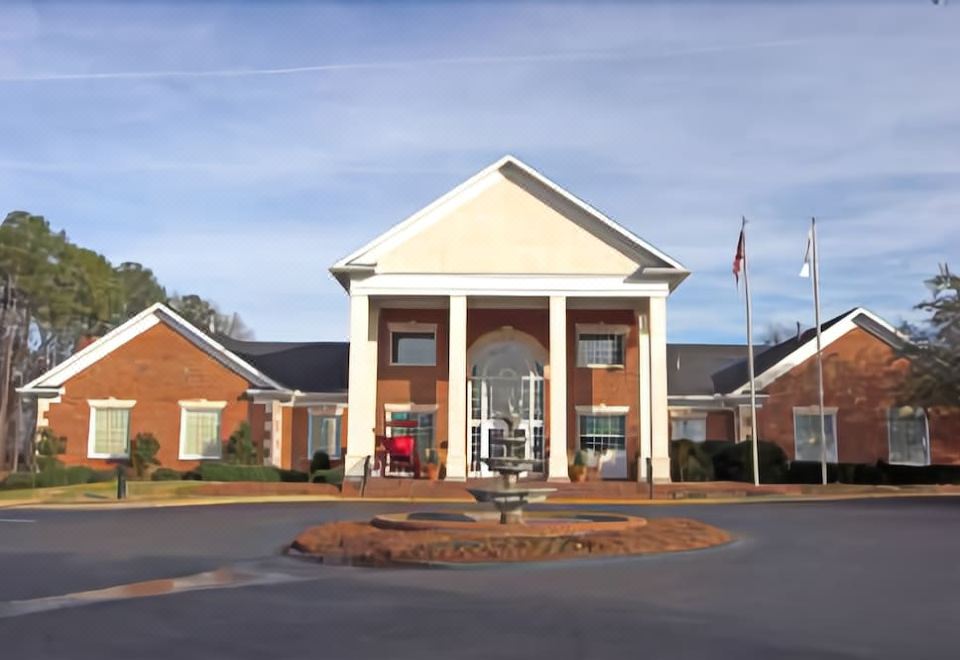 a brick building with white columns and a red roof , situated in front of a flagpole at White Columns Inn