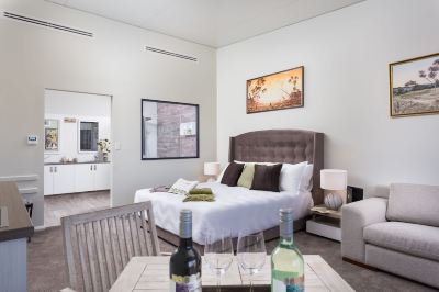 a cozy bedroom with a large bed , two wine glasses on a table , and a painting on the wall at The Swan Valley Retreat