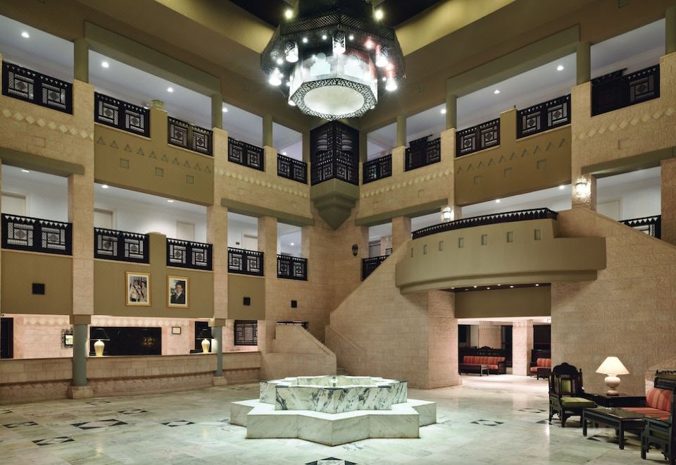 a grand lobby with a chandelier hanging from the ceiling and a staircase leading to an upper level at Grand Mercure Petra