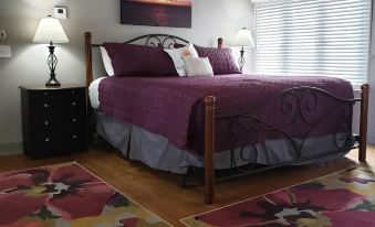 a cozy bedroom with a wooden bed , purple bedding , and two lamps on either side of the bed at Plum Point Lodge