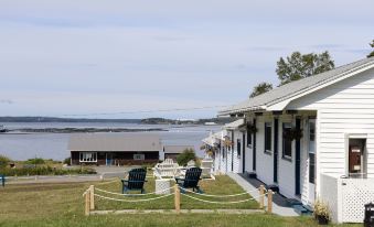 a small , white building with a grassy yard in front of it , where two chairs and a picnic table at Friars Bay Inn & Cottages