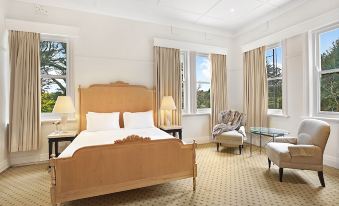 a large bedroom with a king - sized bed , multiple chairs , and windows with curtains in the room at The Robertson Hotel