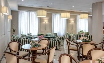 a room with a variety of chairs and tables , some of which are green and white striped at Hotel Boston