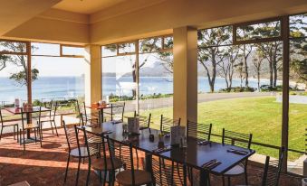 a dining room with a table set for breakfast , surrounded by windows overlooking the ocean at Lufra Hotel and Apartments