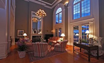 a spacious living room with high ceilings , large windows , and comfortable furniture arranged around a fireplace at Claremont Inn & Winery