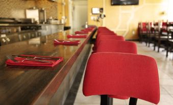 a row of red chairs in front of a long wooden counter with a television on the wall at The Dixie Hollywood