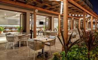 an outdoor dining area at a restaurant , with tables and chairs arranged for guests to enjoy their meals at Sheraton Kauai Coconut Beach Resort