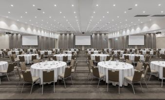 A spacious ballroom is arranged with round tables and chairs for an event at Rydges Resort Hunter Valley, an EVT hotel