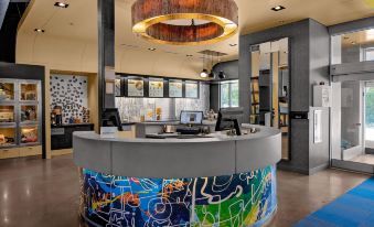 a modern office reception area with a large round table and colorful graffiti on the walls at Aloft Chapel Hill