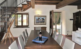 a large wooden dining table with white chairs and a bottle of wine placed on it at Villa