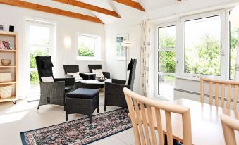 a dining room with a wooden ceiling and large windows , featuring black chairs and a dining table at Henne