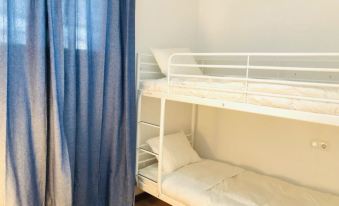 a bunk bed with a ladder is situated next to a window with blue curtains at Bellevue
