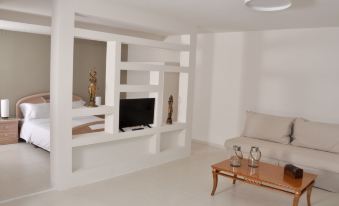 a white living room with a couch , coffee table , and a television on a shelf at Azure