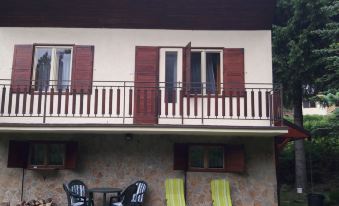 a two - story house with a red and white balcony , green chairs , and a stone patio at Baracka