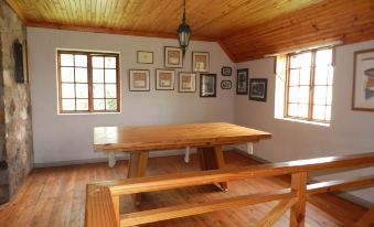 a wooden table and bench are in a room with windows , and framed pictures on the wall at Field and Stream
