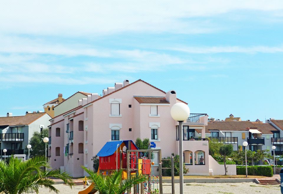 a pink house with a playground in front of it and a blue sky above at Antigua