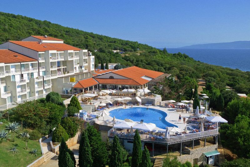 a large resort with multiple buildings , a swimming pool , and lush greenery surrounding the area at Valamar Bellevue Resort