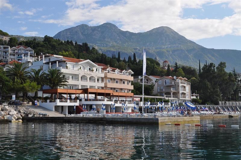 a row of houses with umbrellas and tents are situated on the shore of a lake at Hotel Perla