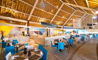 a large dining room with blue chairs and tables , and a thatched roof on the ceiling at Fiesta Resort All Inclusive Central Pacific - Costa Rica