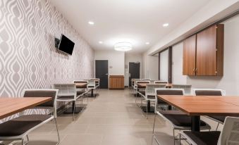 a dining area with several tables and chairs , a television on the wall , and gray wallpaper at Microtel Inn & Suites by Wyndham Sweetwater