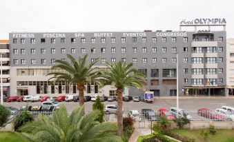 a large building with palm trees in front of it , possibly a hotel or a conference center at Hotel Olympia Valencia