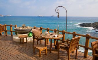 a wooden deck with a dining table and chairs overlooking the ocean , creating a serene and inviting atmosphere at Cala de Mar Resort & Spa Ixtapa