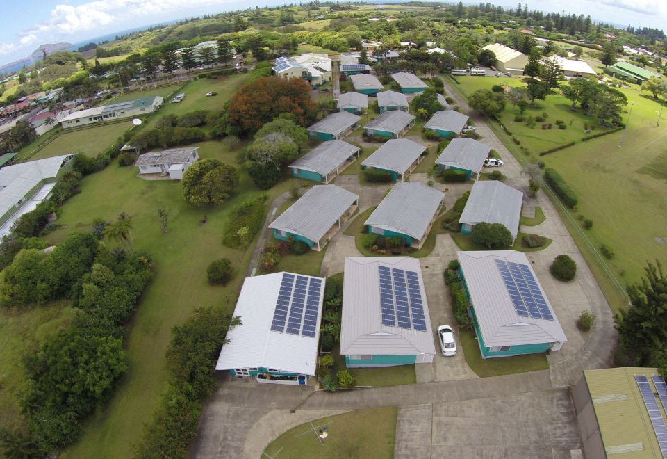 aerial view of a row of houses with solar panels on their roofs , surrounded by green grass and trees at Aloha Apartments