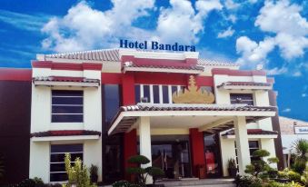 a large hotel building with a red and white facade , situated in a grassy field at Hotel Bandara Syariah