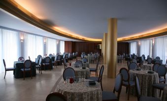 a large dining room with numerous tables and chairs arranged for a group of people to enjoy a meal together at Hotel Royal