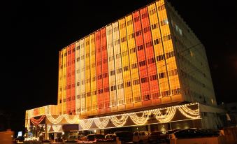 a large , modern building with many windows lit up at night , surrounded by cars on the street at Moti Mahal