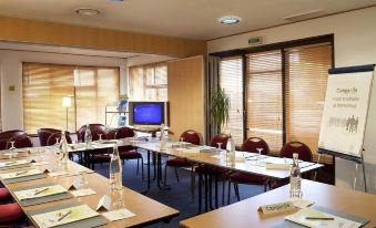 a conference room with several tables and chairs , a tv , and water bottles on each table at Campanile Villejust - ZA Courtaboeuf