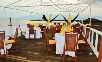 a large white tent with a wooden floor and tables set up for an outdoor event , surrounded by chairs and umbrellas at Grand Hotel Excelsior Port Royal