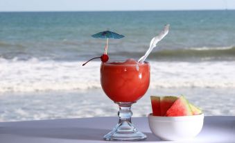 a glass of watermelon juice is on a table with a beach view in the background at Hotel Estero y Mar