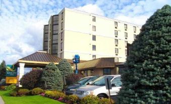 a parking lot with cars parked in front of a large building , surrounded by greenery at Quality Inn & Suites Bay Front