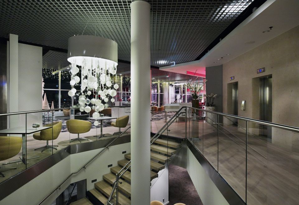 a modern hotel lobby with a large chandelier hanging from the ceiling and multiple chairs on the stairs at Gothia Towers & Upper House