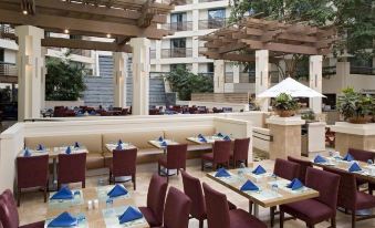 an outdoor dining area at a hotel , with several tables and chairs arranged for guests to enjoy a meal at Hyatt Regency San Francisco Airport