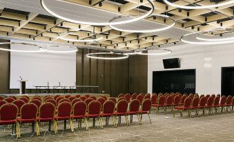 There is a large conference room with red chairs and grey carpeting, featuring floor-to-ceiling windows at Remis Hotel