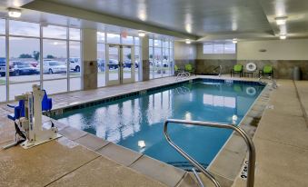 a large swimming pool with a metal ladder and chairs in front of windows overlooking a parking lot at Holiday Inn Roswell