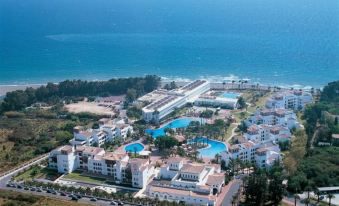 a large resort complex with multiple buildings and pools is situated near the ocean , providing a panoramic view of the surrounding landscape at Ikos Andalusia