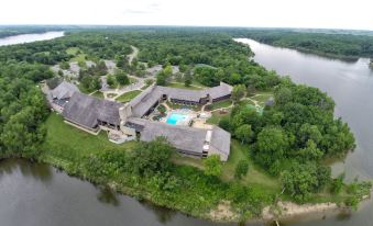 an aerial view of a resort with multiple buildings , swimming pools , and lush greenery surrounding a river at Deer Creek Lodge & Conference Center