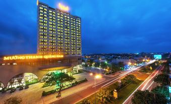 a large hotel building with a yellow sign is surrounded by trees and roads at night at Muong Thanh Grand Quang Nam