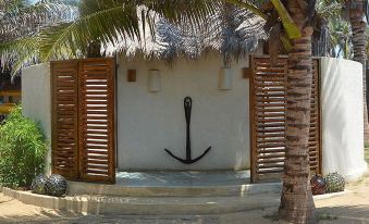a white wall with a wooden anchor mounted on it , surrounded by a palm tree at Dolphin Beach Resort