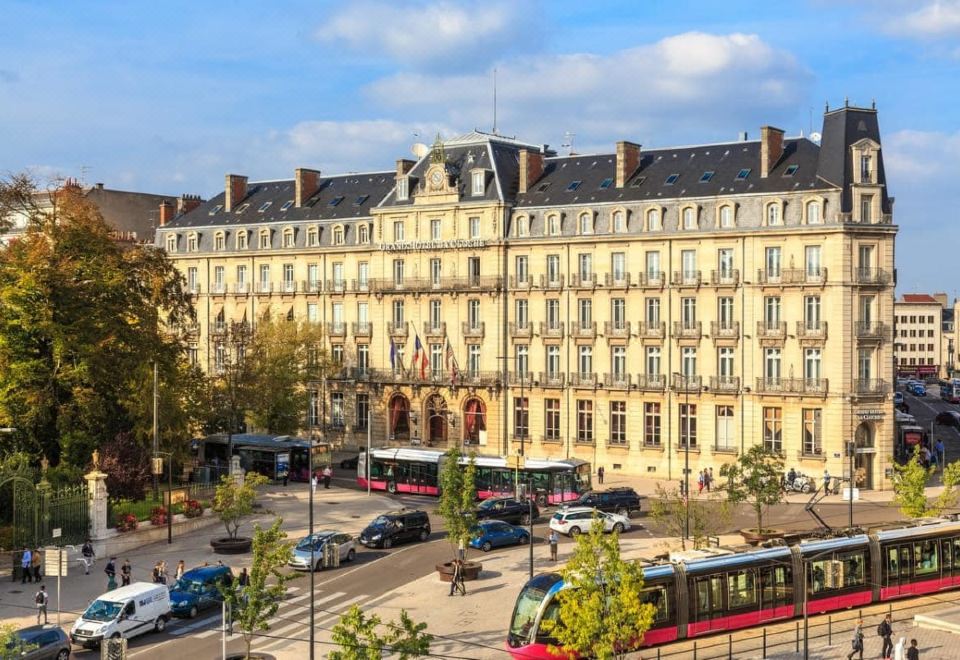 a busy city street with multiple cars , buses , and trucks , as well as pedestrians walking on the sidewalk at Grand Hôtel la Cloche Dijon - MGallery