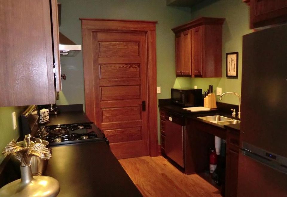 a kitchen with dark wood cabinets , a stove top oven , and an open door leading to another room at Lesmeister Guesthouse