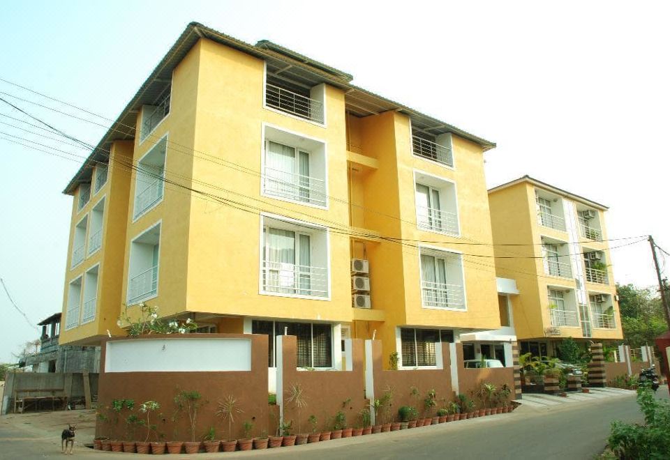 a yellow building with white trim , situated in a residential neighborhood with several cars parked nearby at Le Magnifique