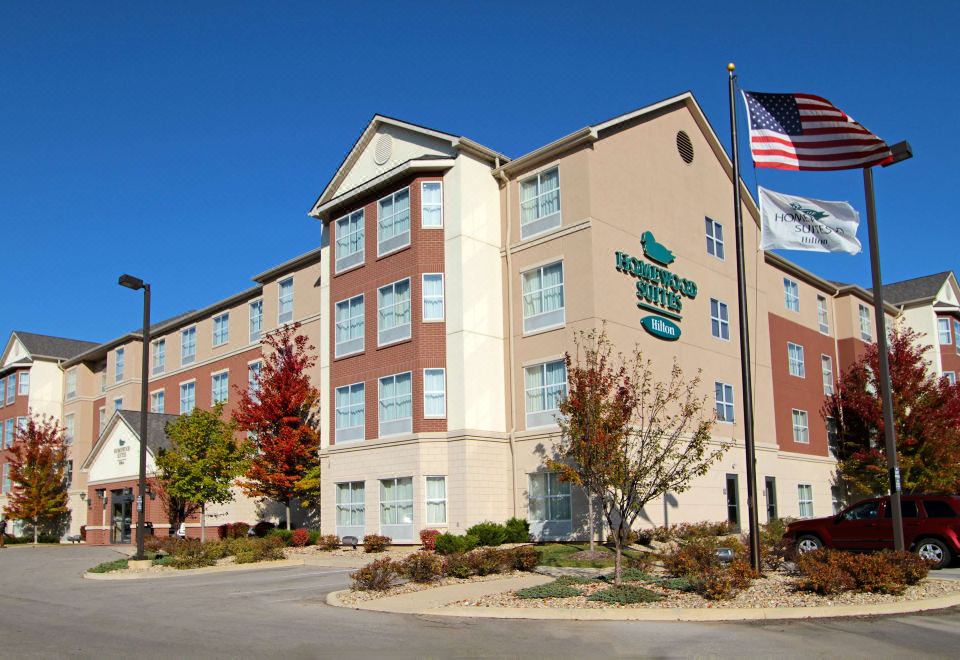 an exterior view of a holiday inn express hotel with a large building in the background at Homewood Suites by Hilton Bloomington